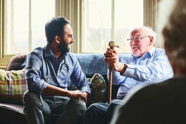 Image of a GP talking to a man in a carehome