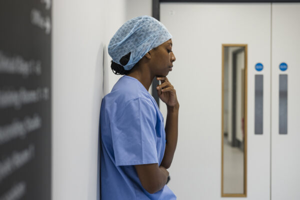 NHS worker in scrubs deep in thought