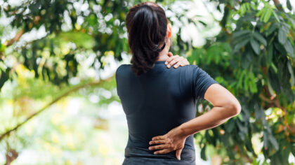 Young woman holding her lower back as if in pain