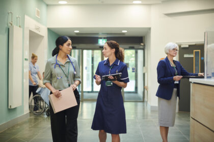 Two clinicians talking while walking down a hospital corridor
