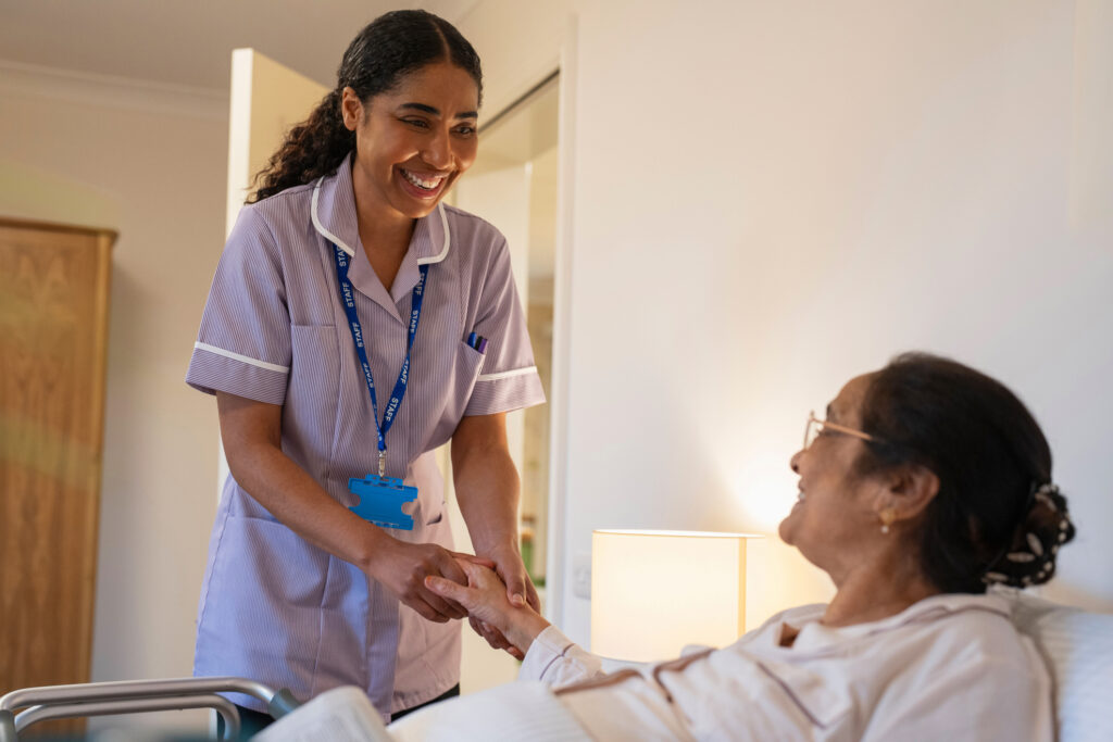 Nurse visiting senior lady in her hospital bed