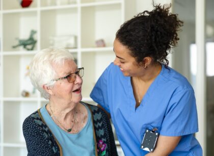 Female care professional with senior woman in her home, both are smiling.