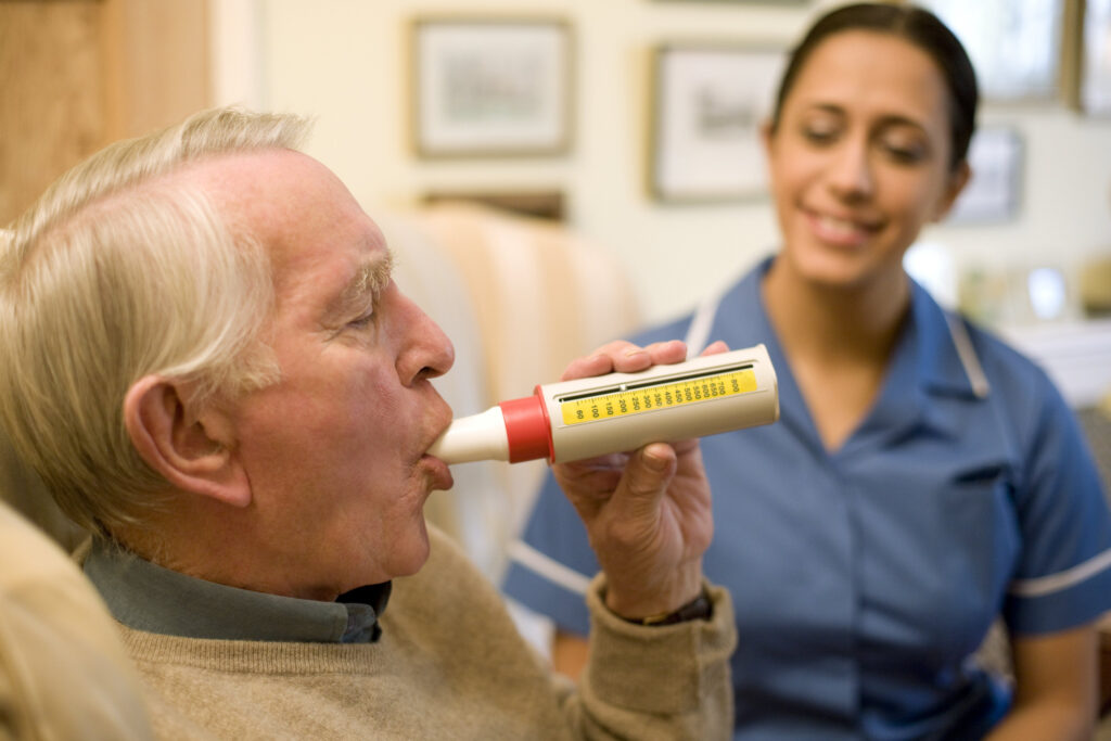 Senior man blowing into a peak flow meter