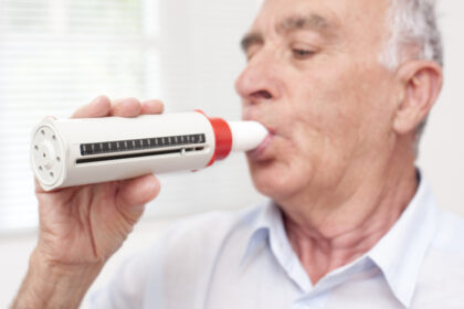 Senior man exhaling into a peakflow reader.